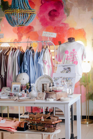 Handlettered apparel and gifts in front of a floral mural at The Willow Collective